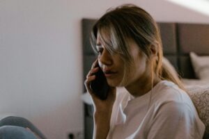 A worried woman on a phone call indoors, conveying stress and emotion.