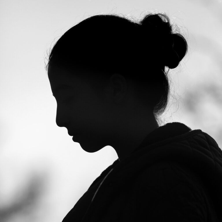 Artistic black and white silhouette of a woman with a hair bun captured in profile view.
